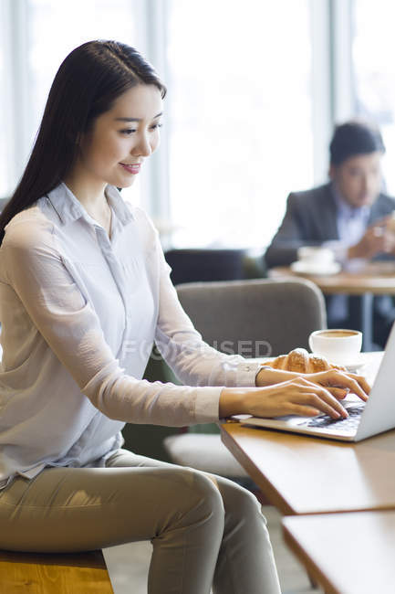 Femme chinoise travaillant avec un ordinateur portable dans un café — Photo de stock