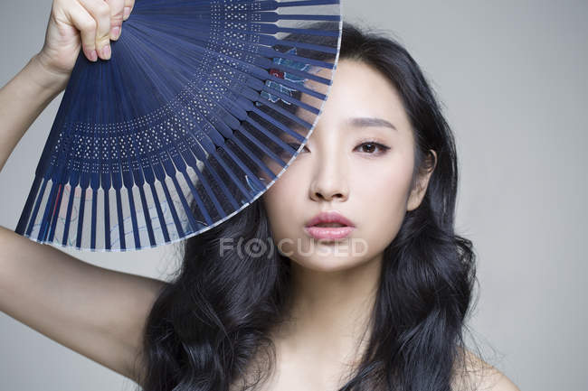 Китаянка, прикрывающая лицо складным вентилятором — стоковое фото