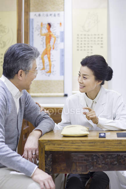 Female Chinese doctor talking with senior patient — Stock Photo