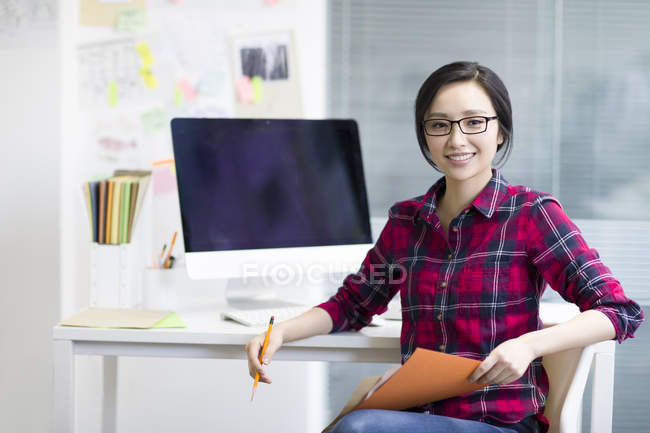 Китаянка-дизайнер сидит в офисе с альбомом эскизов — стоковое фото
