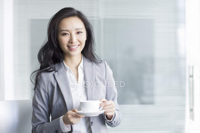 Chinese businesswoman taking coffee break at work — Stock Photo
