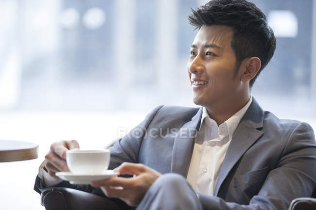 Hombre chino bebiendo café en la cafetería - foto de stock