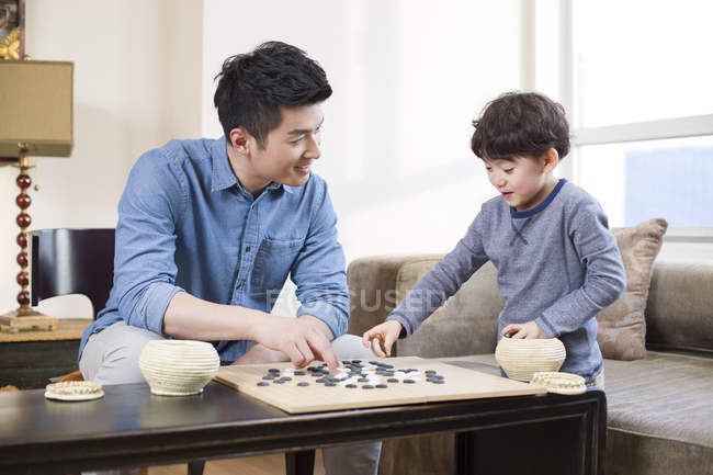 Chino padre e hijo jugando juego de ir en casa - foto de stock
