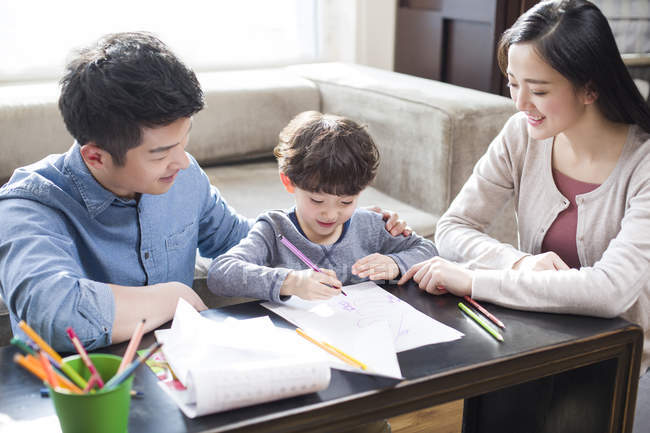 Genitori cinesi che aiutano il figlio con i compiti — Foto stock