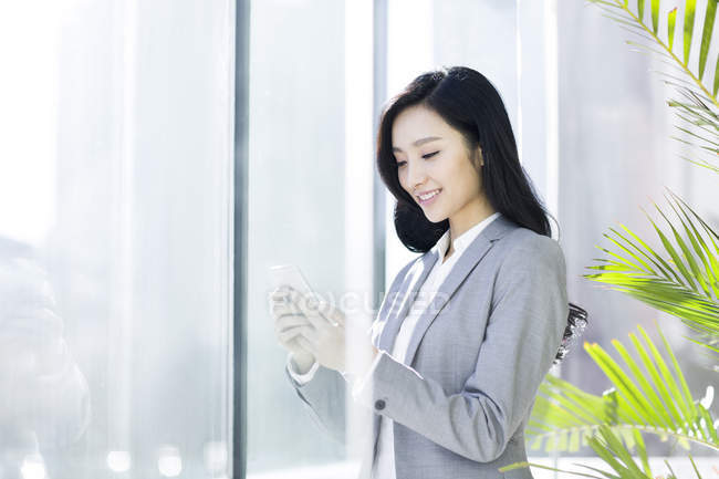 Китайская предпринимательница использует смартфон в офисном здании — стоковое фото