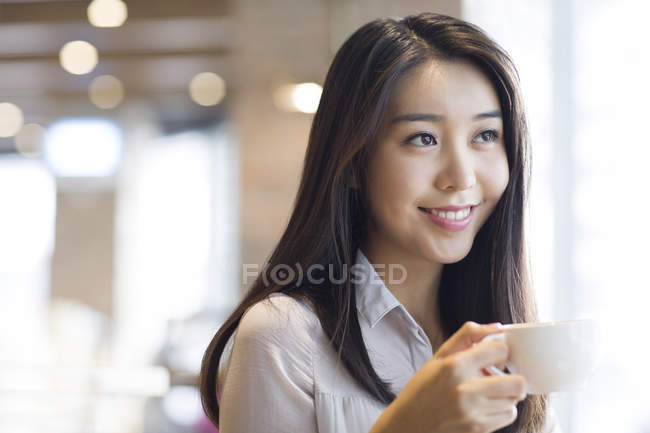 Mujer china tomando café en la cafetería - foto de stock