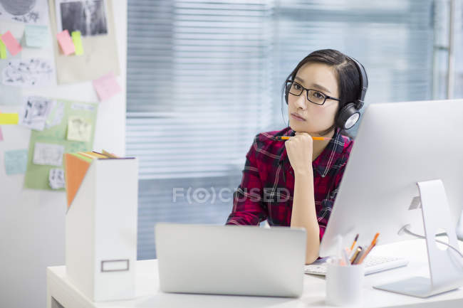 Femme chinoise écoutant de la musique au bureau — Photo de stock