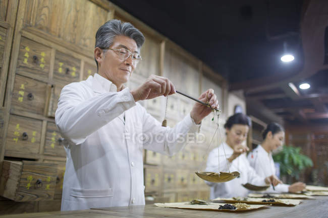 Medici cinesi che pesano erbe nella farmacia tradizionale — Foto stock
