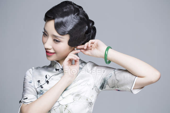 Китайська жінка в традиційному одязі, надягаючи сережки — стокове фото