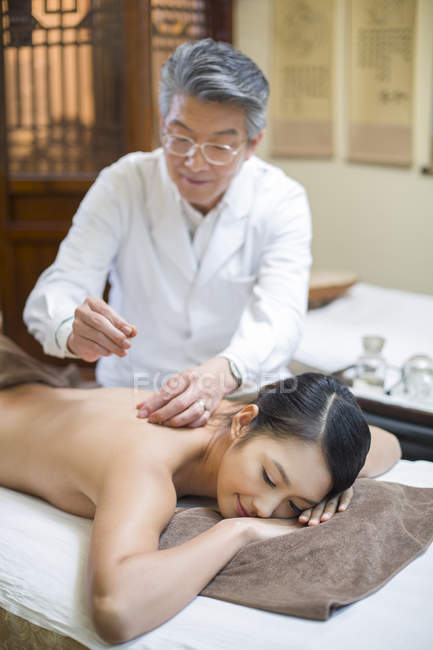 Senior doctor performing acupuncture treatment on female patient — Stock Photo