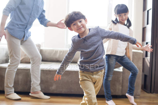 Chinesische Kinder tanzen mit Vater im Wohnzimmer — Stockfoto