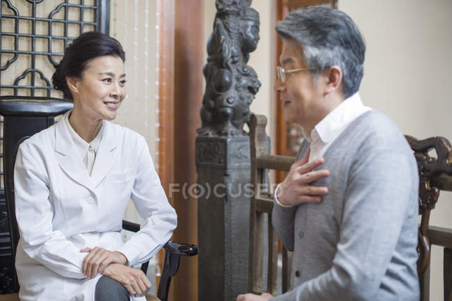 Femme médecin chinois parler avec le patient âgé — Photo de stock