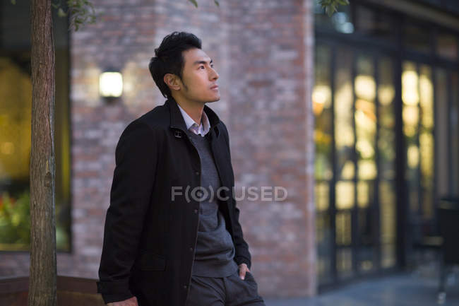 Nachdenklicher Chinese steht auf der Straße und schaut auf — Stockfoto
