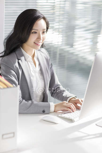 Empresaria china usando computadora en la oficina - foto de stock