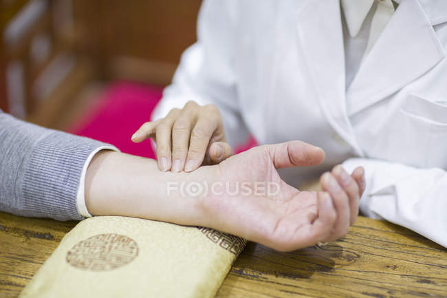 Female doctor taking pulse of patient — Stock Photo