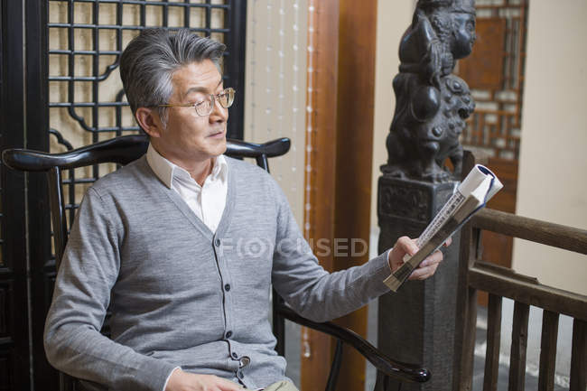 Senior cinese uomo lettura libro in sedia — Foto stock