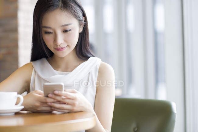 Donna cinese che utilizza smartphone in caffetteria — Foto stock