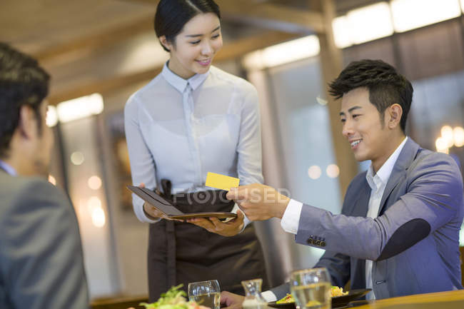 Китайские бизнесмены платят кредитной картой в ресторане — стоковое фото