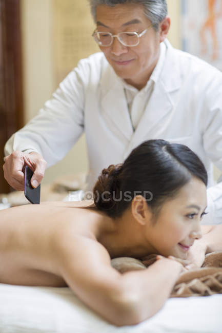Médecin chinois principal effectuant un massage de déchirure sur la patiente — Photo de stock