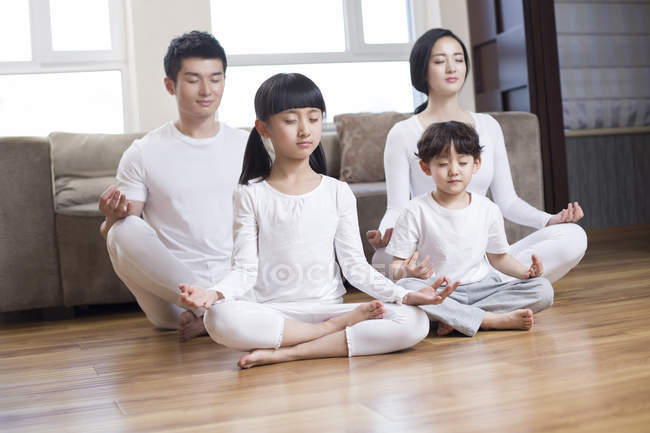 Chinesische Familie meditiert im Wohnzimmer — Stockfoto