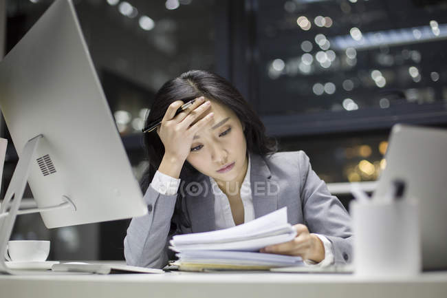 Chinese businesswoman working late with documents in office — Stock Photo
