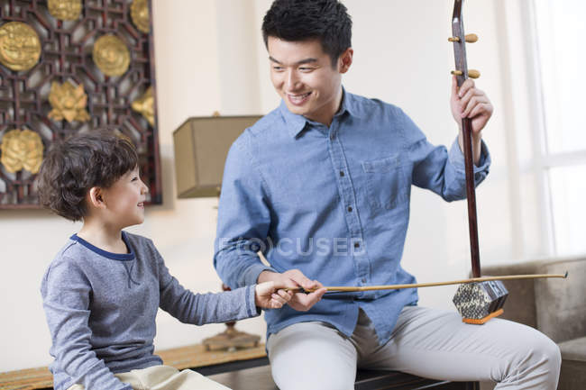 Chinese father teaching son traditional musical instrument erhu — Stock Photo