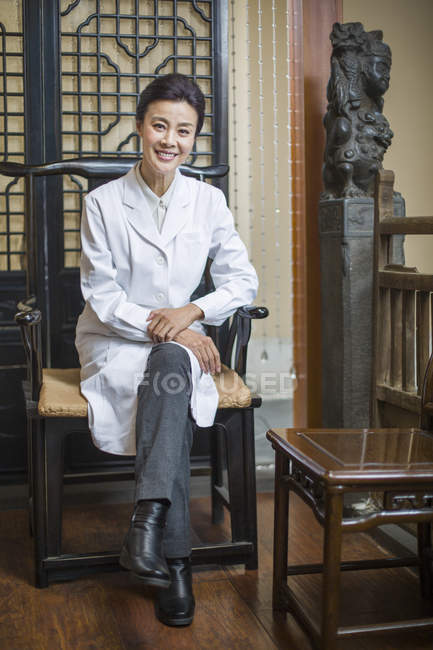 Donna medico cinese seduto sulla sedia e guardando in macchina fotografica — Foto stock