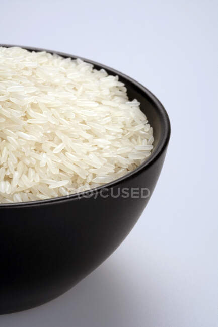 Close up de arroz em tigela preta no fundo branco — Fotografia de Stock