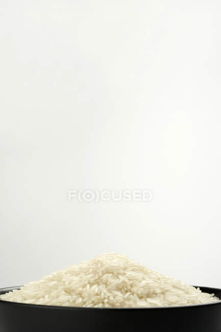 Pilha de arroz não cozido em tigela preta com espaço de cópia — Fotografia de Stock