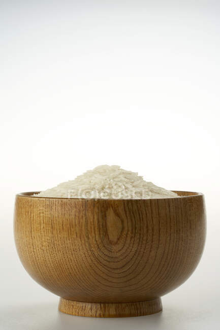 Pilha de arroz em tigela de madeira no fundo branco — Fotografia de Stock