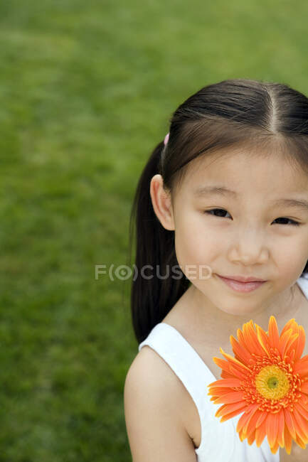 Jeune fille chinoise tenant une fleur dans le parc — Photo de stock