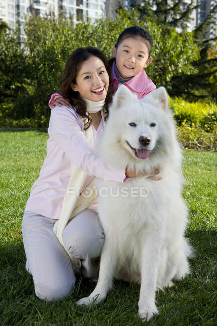 Mãe chinesa e filha com o cão da família — Fotografia de Stock