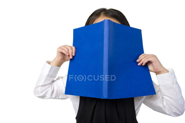 Little Chinese girl covers her face with a book — Stock Photo