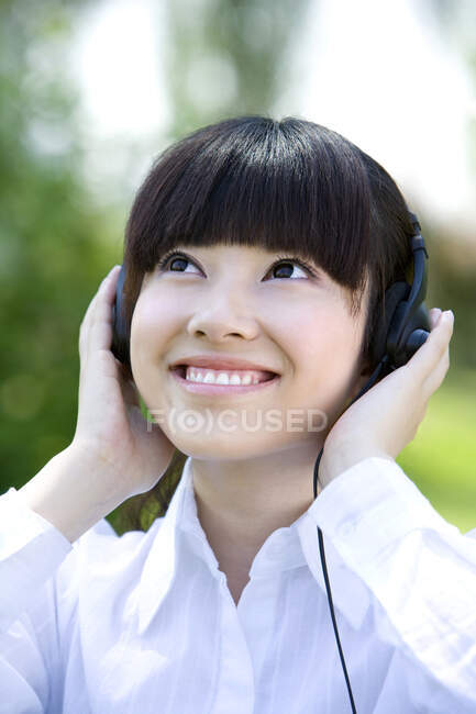 Mujer china usando auriculares y sonriendo - foto de stock