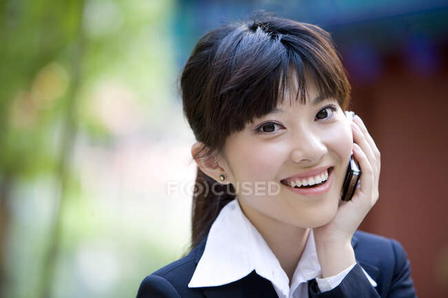 Китайка розмовляє по мобільному телефону і посміхається — стокове фото