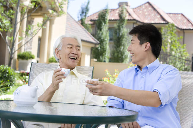Chinese father and son chatting and having tea — Stock Photo