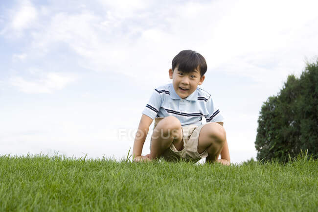 Китайский мальчик сидит на траве — стоковое фото