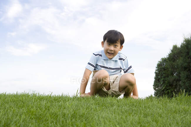 Chinese boy sitting on the grass — Stock Photo