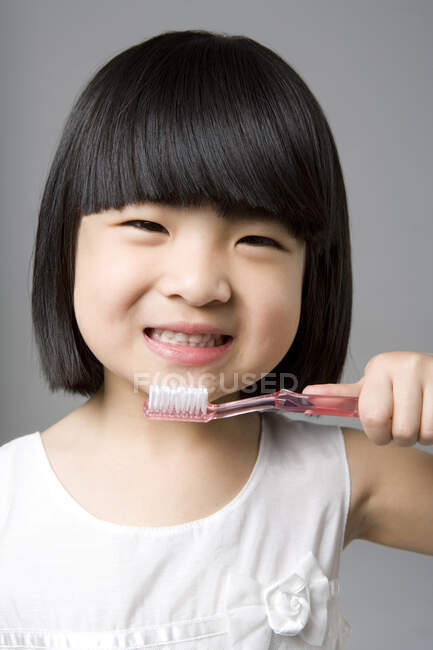 Pequena menina chinesa feliz com escova de dentes — Fotografia de Stock