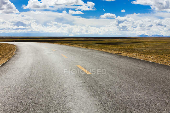 Strada con vista sulle montagne lontane e cielo nuvoloso, Tibet, Cina — Foto stock