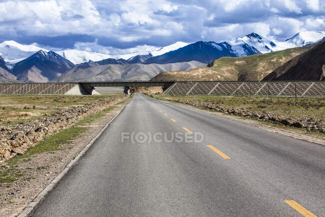 Ponte su strada con vista sulle montagne e cielo nuvoloso, provincia di Qinghai — Foto stock