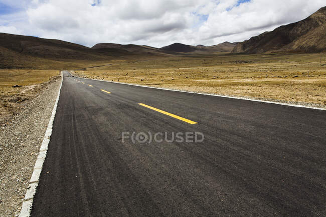 Road with mountains view and cloudy sky, Tibet, China — Stock Photo