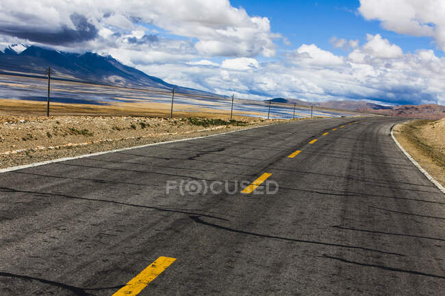Strada con vista sulle montagne e cielo nuvoloso, Tibet, Cina — Foto stock