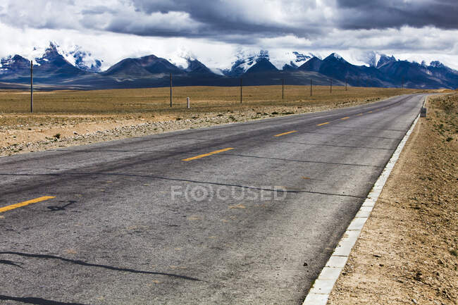 Estrada com vista montanhas e céu nublado, Tibete, China — Fotografia de Stock