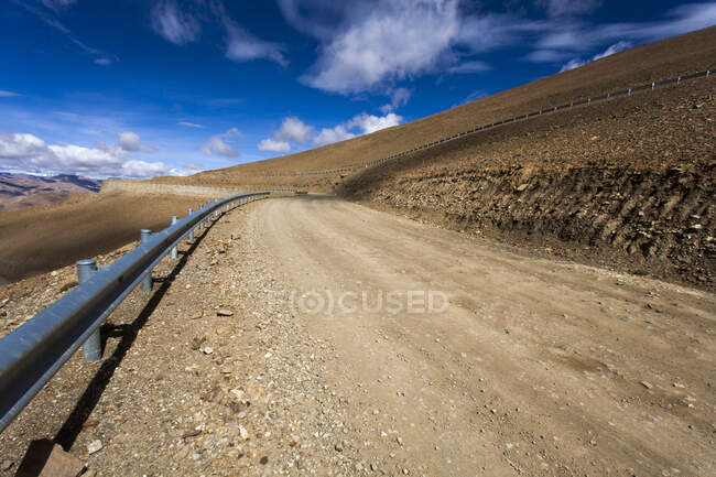 Route avec vue sur les montagnes et ciel nuageux, Tibet, Chine — Photo de stock