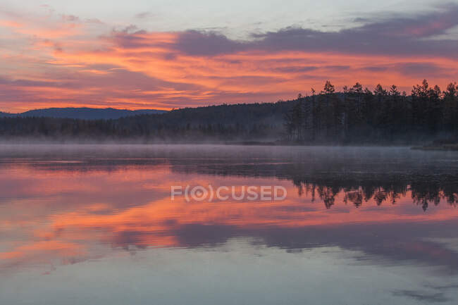 Lago con el reflejo del cielo puesta del sol y montañas - foto de stock