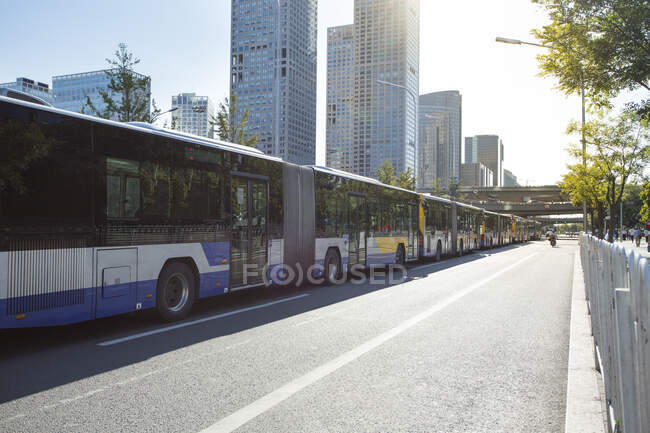 Grand bus se déplaçant sur la route à la rue ensoleillée — Photo de stock