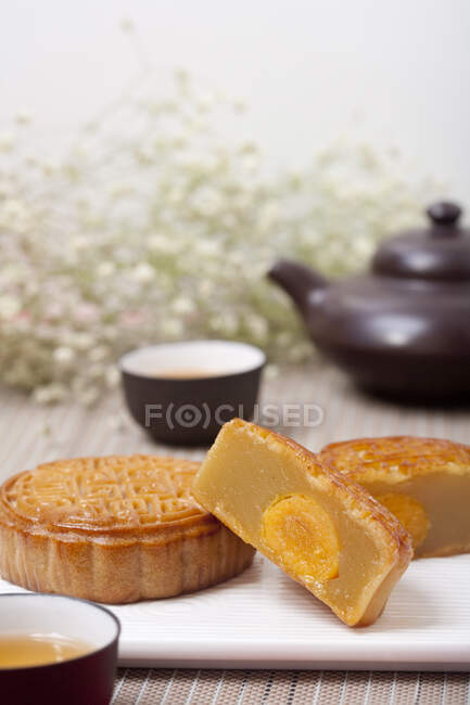 Mondkuchen auf Teller serviert mit Tee in Tassen und Kannen — Stockfoto