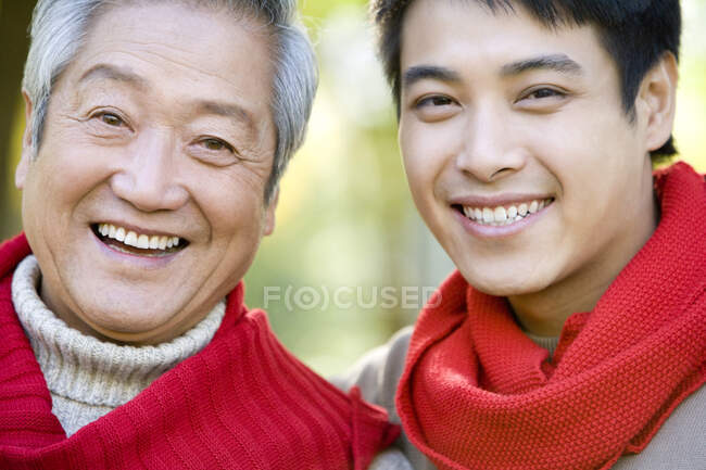 Padre chino e hijo adulto disfrutando de un parque en otoño - foto de stock