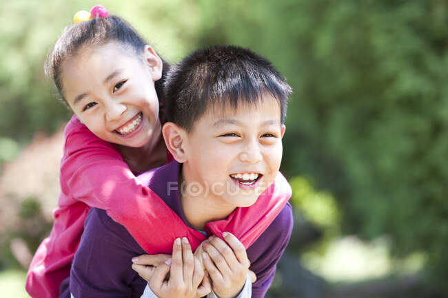 Portrait de jeune chinois garçon donnant fille piggyback tour — Photo de stock